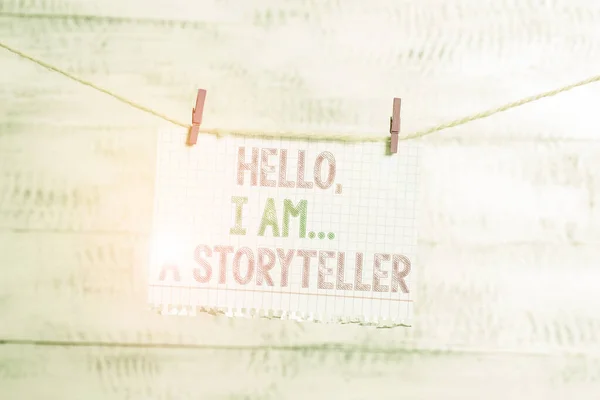 Writing note showing Hello I Am A Storyteller. Business photo showcasing introducing yourself as novels article writer Clothesline clothespin rectangle shaped paper reminder white wood desk.