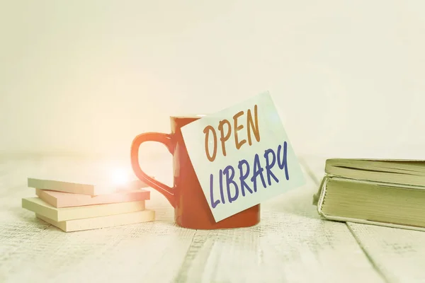 Text sign showing Open Library. Conceptual photo online access to analysisy public domain and outofprint books Coffee cup blank sticky note stacked note pads books retro old wooden table.