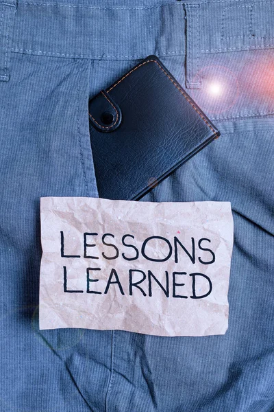 Word writing text Lessons Learned. Business concept for the knowledge or understanding gained by experience Small little wallet inside man trousers front pocket near notation paper.