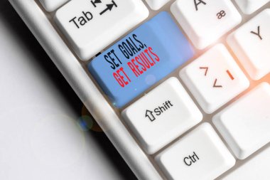 Hedefleri Belirle Sonuçlarını gösteren not yazılıyor. İş fotoğrafı gösterimi. Beyaz arkaplanının üzerinde nota kağıdı bulunan beyaz pc klavye için hedefleri gerçekleştirmek için çalışır..