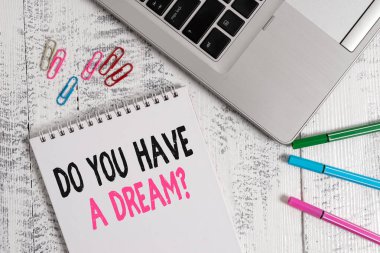 Handwriting text Do You Have A Dream Question. Concept meaning asking someone about life goals Achievements Slim metallic laptop blank spiral notepad pens clips lying wooden table. clipart