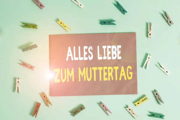 Conceptual hand writing showing Alles Liebe Zum Muttertag. Business photo showcasing Happy Mothers Day Love Good wishes Affection Colored clothespin rectangle shaped paper blue background.