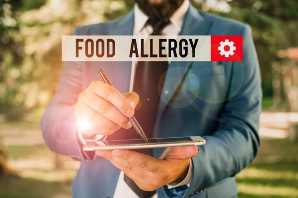 Text sign showing Food Allergy. Conceptual photo an abnormal immune response after eating a certain food Businessman in blue suite stands with mobile phone in hands.