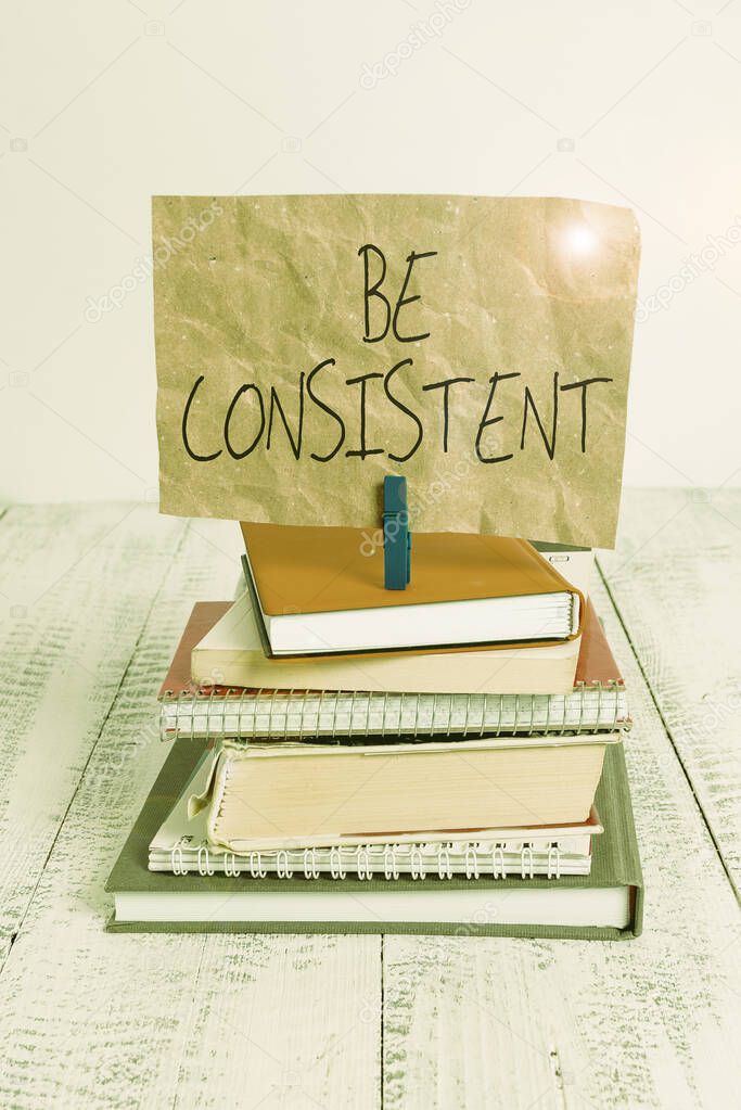 Writing note showing Be Consistent. Business photo showcasing Uniform Persistent Firm Unalterable Even Unchanging Rapport pile stacked books notebook pin color reminder white wooden.