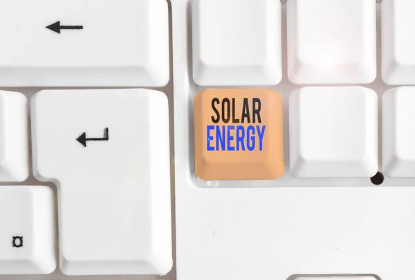 Texto manuscrito Energía Solar. Concepto que significa radiación del Sol capaz de producir calor o electricidad Teclado blanco para PC con papel de nota vacío sobre el espacio de copia de la tecla de fondo blanco . —  Fotos de Stock