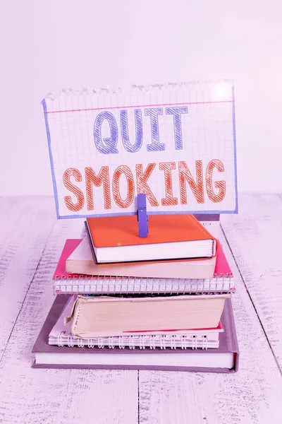 Sinal de texto mostrando parar de fumar. Processo fotográfico conceitual de descontinuar fumar tabaco ou cessação pilha empilhados livros caderno pin clothespin colorido lembrete branco de madeira . — Fotografia de Stock