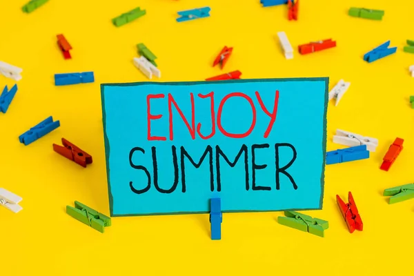 Sinal de texto mostrando Aproveite o verão. Foto conceitual fazendo uma pausa da escola e passar férias na praia Papéis de roupa coloridos vazio lembrete amarelo chão fundo escritório . — Fotografia de Stock