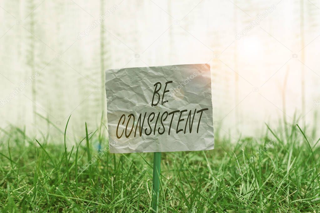 Conceptual hand writing showing Be Consistent. Business photo text Uniform Persistent Firm Unalterable Even Unchanging Rapport Plain paper attached to stick and placed in the grassy land.