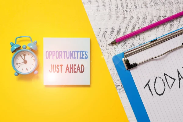 Writing note showing Opportunities Just Ahead. Business photo showcasing Advantageous circumstances Perseverance pays off Notepad clipboard colored paper sheet alarm clock wooden background. — Stok fotoğraf