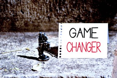 Word writing text Game Changer. Business concept for way that effects a major shift in the current analysisner of doing Bronze Knight Chessman Blank Spiral Notepad Sheet Folded in Half Dry Leaves.