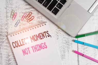 Handwriting text Collect Moments Not Things. Concept meaning Happiness philosophy enjoy simple life facts Slim metallic laptop blank spiral notepad pens clips lying wooden table.
