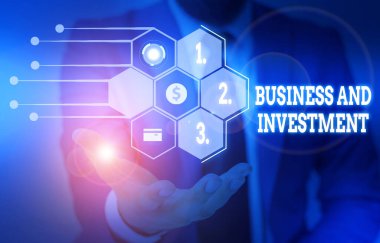 Writing note showing Business And Investment. Business photo showcasing putting your money in field to increase them Male wear formal suit presenting presentation smart device.