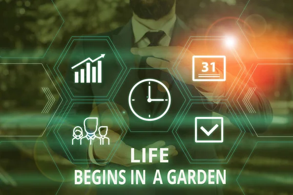 Word writing text Life Begins In A Garden. Business concept for Agriculture Plants growing loving for gardening Male human wear formal work suit presenting presentation using smart device.