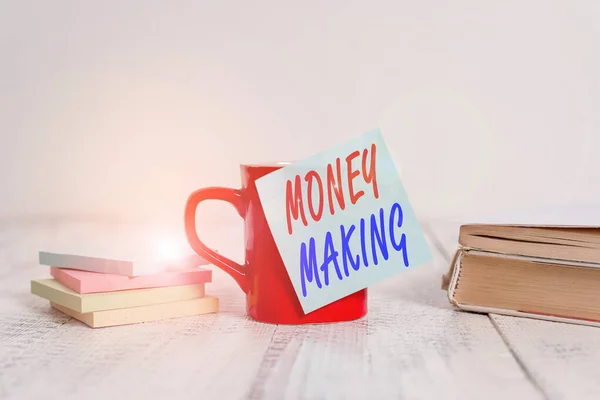 Text sign showing Money Making. Conceptual photo producing a profit especially with little effort Profitable Coffee cup blank sticky note stacked note pads books retro old wooden table.