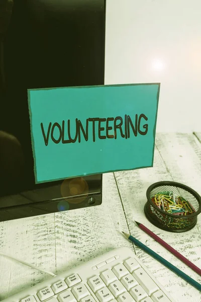 Conceptual hand writing showing Volunteering. Business photo text Provide services for no financial gain Willingly Oblige Note paper taped to black screen near keyboard stationary. — ストック写真