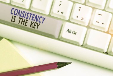 Tutarlılığı gösteren metin işareti anahtardır. Beyaz arkaplan anahtar boşluğunun üzerinde boş not kağıdı bulunan bir alışkanlık oluşturma işlemi olan kavramsal fotoğraf tam adanmışlığı.