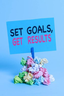 Text sign showing Set Goals Get Results. Conceptual photo Establish objectives work for accomplish them Reminder pile colored crumpled paper clothespin reminder blue background.