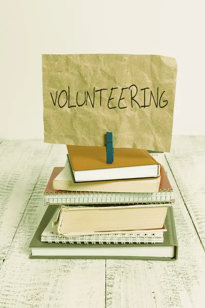 Writing note showing Volunteering. Business photo showcasing Provide services for no financial gain Willingly Oblige pile stacked books notebook pin color reminder white wooden. — 图库照片