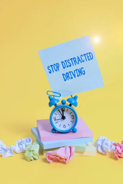 Sinal de texto mostrando Stop Distracted Driving. Foto conceitual pedindo para ter cuidado atrás da roda motriz lentamente Relógio despertador nota pegajosa papel bolas blocos de notas empilhados fundo colorido . — Fotografia de Stock