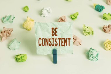 El yazısı, tutarlı ol. Kavram anlamı: Uniform Daimi Firma Değiştirilemez Değişmeyen Rapport Renkli kağıtlar boş hatırlatıcı beyaz zemin çamaşır mandalı.