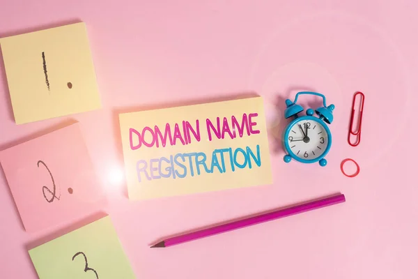 Writing note showing Domain Name Registration. Business photo showcasing Own an IP Address Identify a particular Webpage Blank notepads marker rubber band alarm clock clip colored background.