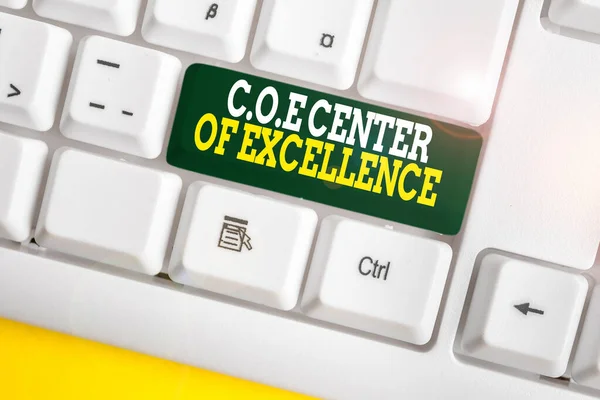 Writing note showing Coe Center Of Excellence. Business photo showcasing being alpha leader in your position Achieve White pc keyboard with note paper above the white background.