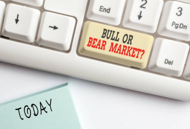 Boğa ya da ayı pazarı sorusunu gösteren kavramsal el yazısı. İş fotoğrafı sergisi birine pazarlama metodunu soruyor beyaz arkaplanının üstünde not kağıdı olan beyaz bilgisayar klavyesi.