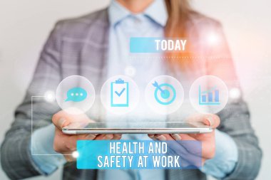 Writing note showing Health And Safety At Work. Business photo showcasing Secure procedures prevent accidents avoid danger Female human wear formal work suit presenting smart device.
