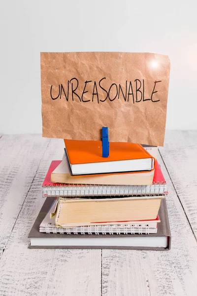 Writing note showing Unreasonable. Business photo showcasing Beyond the limits of acceptability or fairness Inappropriate pile stacked books notebook pin color reminder white wooden.