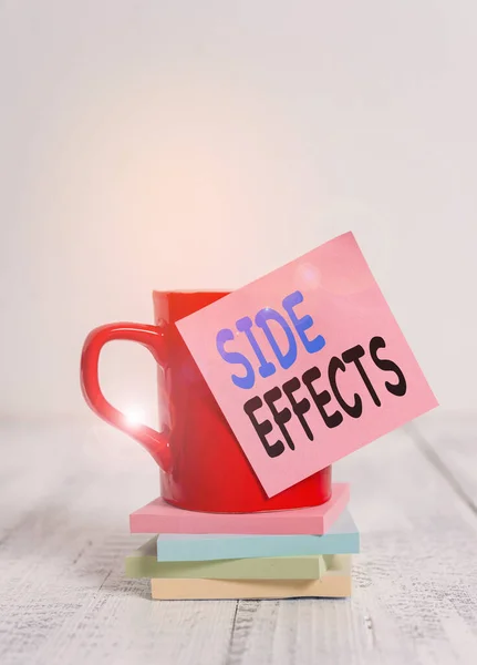 Handwriting text Side Effects. Concept meaning secondary undesirable effect of a drug or medical treatment Coffee cup blank sticky note stacked note pads retro retro wooden table.