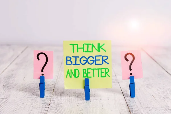 Conceptual hand writing showing Think Bigger And Better. Business photo text no Limits be Open minded Positivity Big Picture Crumbling sheet with paper clips placed on the wooden table.