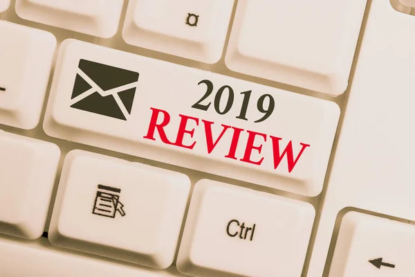Text sign showing 2019 Review. Conceptual photo New trends and prospects in tourism or services for 2019 White pc keyboard with empty note paper above white background key copy space. — 스톡 사진