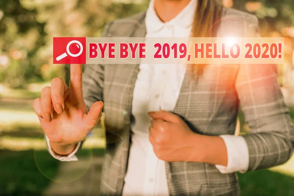 Текст рукописного тексту "Bow Bye 2019 Hello 2020". Концепція, що означає попрощатися з минулим роком і привітати ще одну хорошу ділову жінку в природі, вказуючи пальцем на порожній простір . — стокове фото