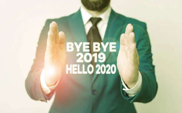 Texto de escritura de palabras Bye Bye 2019 Hello 2020 Concepto de negocio para despedirse del año pasado y dar la bienvenida a otro buen hombre con las manos abiertas en la parte delantera de la mesa. Teléfono móvil y notas en la pestaña —  Fotos de Stock