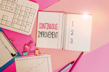 Kelime yazma metni Sürekli Gelişme. Ürün ve süreçleri iyileştirmek için sürdürülen bir iş konsepti. Renkli düz masa üzerine yerleştirilen yazma ekipmanları ve bilgisayar malzemeleri..