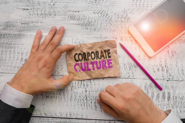 Handwriting text Corporate Culture. Concept meaning pervasive values and attitudes that characterize a company Hand hold note paper near writing equipment and modern smartphone device.