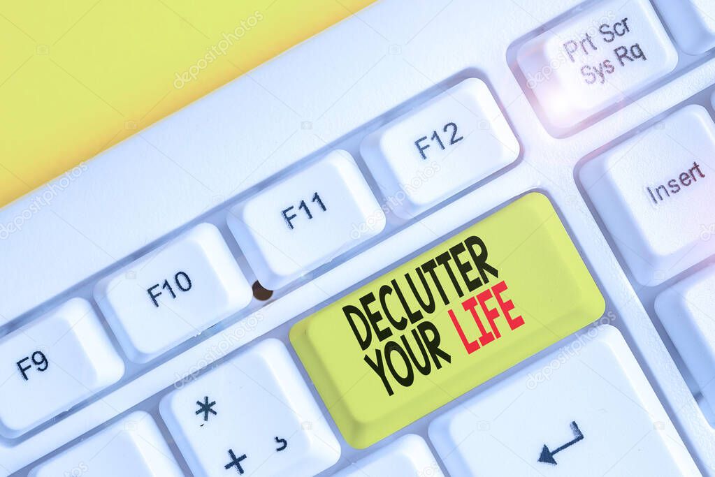 Conceptual hand writing showing Declutter Your Life. Business photo text To eliminate extraneous things or information in life White pc keyboard with note paper above the white background.