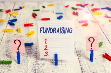 Bağış toplamayı gösteren bir metin işareti. Ahşap masaya yerleştirilen ataçlarla karalama ve parçalanan levhayı belirli bir amaç için para toplama veya üretme kavramsal fotoğraf eylemi.