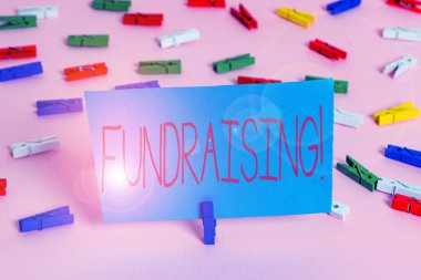 Bağış toplamayı gösteren bir not yazıyorum. Sadaka için mali destek oluşturmak veya renkli clothespin kağıtları boş hatırlatma pembe zemin ofis pin neden arayan İş fotoğraf vitrin.