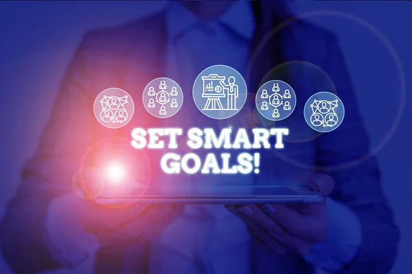 Conceptual hand writing showing Set Smart Goals. Business photo text list to clarify your ideas focus efforts use time wisely Woman wear work suit presenting presentation smart device.