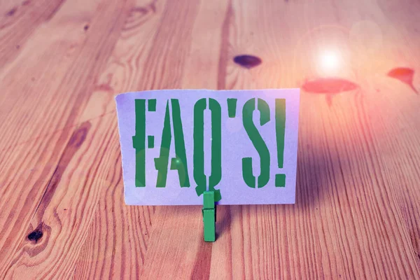Pisanie notatki pokazujące FAQ S. Business Photo prezentuje listę pytań i odpowiedzi odnoszących się do konkretnego tematu drewniana podłoga w rowku Zielona clothespin gniazdo. — Zdjęcie stockowe