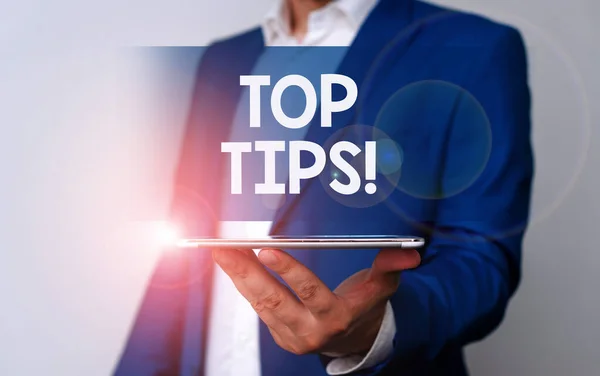 Texto a mano Top Tips. Concepto que significa pequeño pero particularmente útil consejo práctico Hombre en la suite azul y camisa blanca sostiene el teléfono móvil en la mano . —  Fotos de Stock