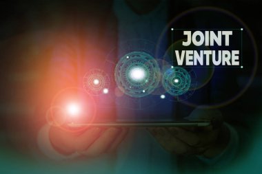 El yazısı metin yazma Joint Venture. Kavram anlamı İşbirliği Düzenleme Taraflar Ortaklık Takım Kadın akıllı cihaz kullanarak sunum sunan resmi iş elbisesi giymek.