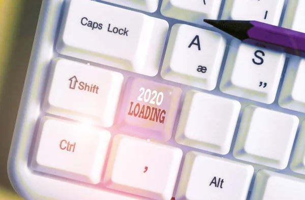 Writing note showing 2020 Loading. Business photo showcasing Advertising the upcoming year Forecasting the future event White pc keyboard with note paper above the white background.