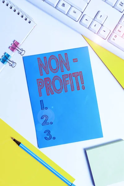 Conceptuele hand schrijven toont non-profit. Zakelijke foto tekst niet maken of uitgevoerd in de eerste plaats te maken van profit organisatie gekleurd papier Binder clip vellen wit Bureau lege ruimte. — Stockfoto