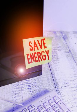 Kelime yazma metni Enerji tasarrufu. Beyaz klavyenin yanındaki siyah bilgisayar monitör ekranına bantlanmış benzer bir sonuç elde etmek için kullanılan güç miktarını azaltmak için iş konsepti.