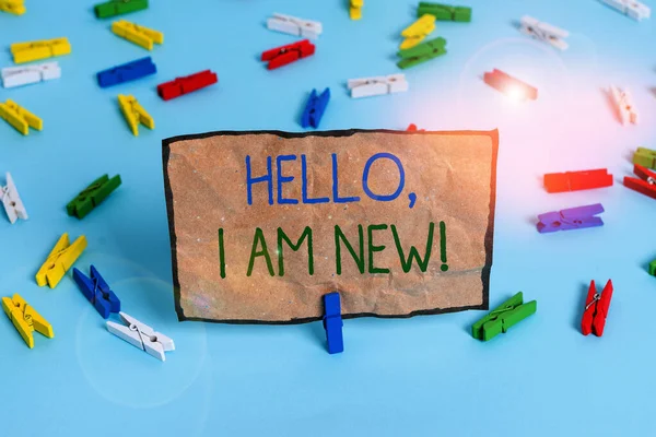 Handwriting text writing Hello I Am New. Concept meaning introducing oneself in a group as fresh worker or student Colored clothespin papers empty reminder blue floor background office pin.