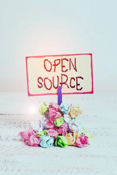 Writing note showing Open Source. Business photo showcasing denoting software which original source code freely available Reminder pile colored crumpled paper clothespin wooden space.