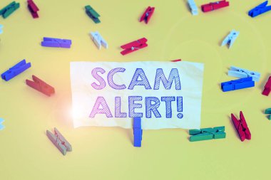 Scam Alert'i gösteren not yazma. İş fotoğraf vitrin hileli onu Renkli clothespin kağıtları boş hatırlatma sarı zemin arka plan ofis ikna ederek kurbandan para elde.