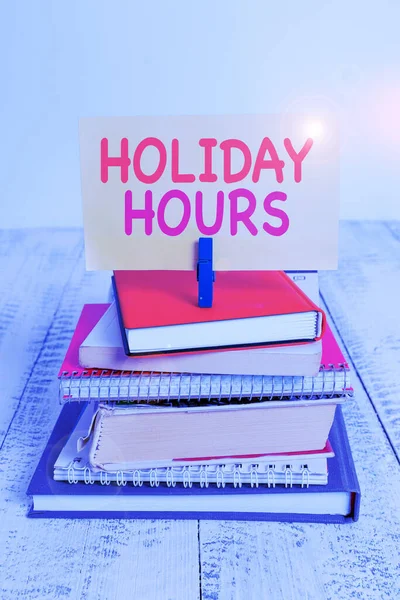 Fogalmi kézzel írásban mutatja Holiday hours. Üzleti fotó szöveg alkalmazottja kap kétszerese a normál fizetni minden órában halom halmozott könyvek notebook PIN színes emlékeztető fehér fából készült. — Stock Fotó